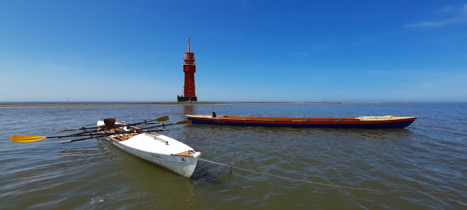 Die Boote "Wilhelm Bette" und "Eisbär" liegen vor der Sandbank, auf der der Leuchtturm "Robbenplate" steht im seichten Wasser vertäut.